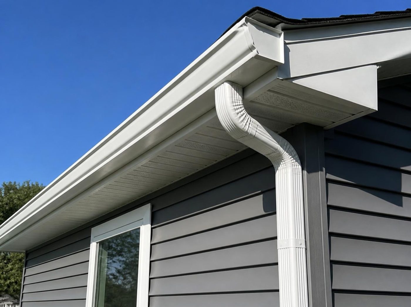 New white gutters and downspout on gray siding